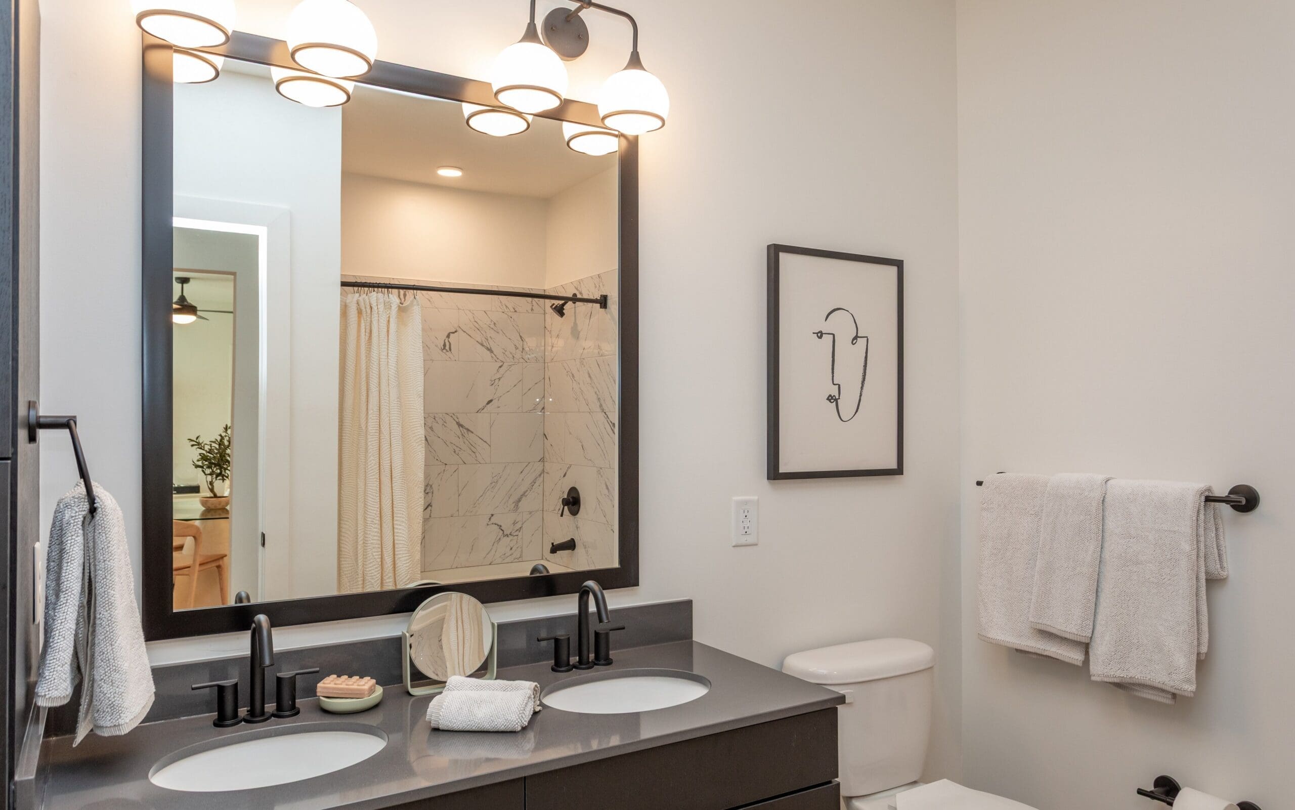 Modern bathroom layout with dark countertops at The Row apartments in Raleigh, NC