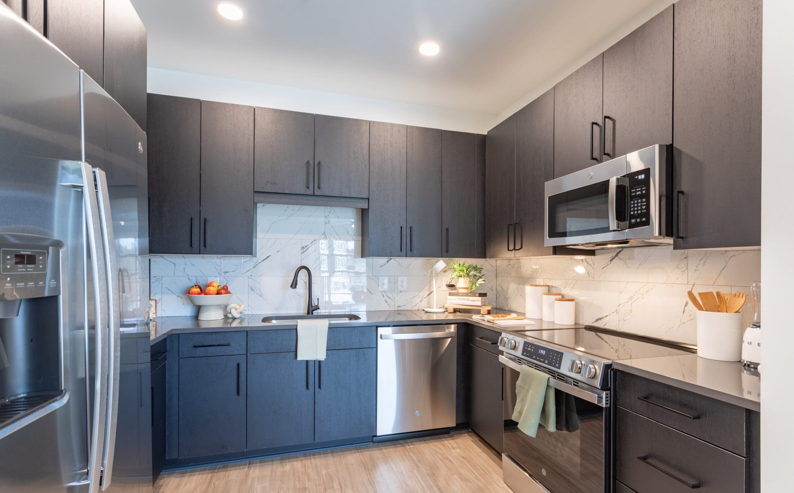 Kitchen with dark cabinets and stainless steel appliances at The Row apartments in Raleigh, NC